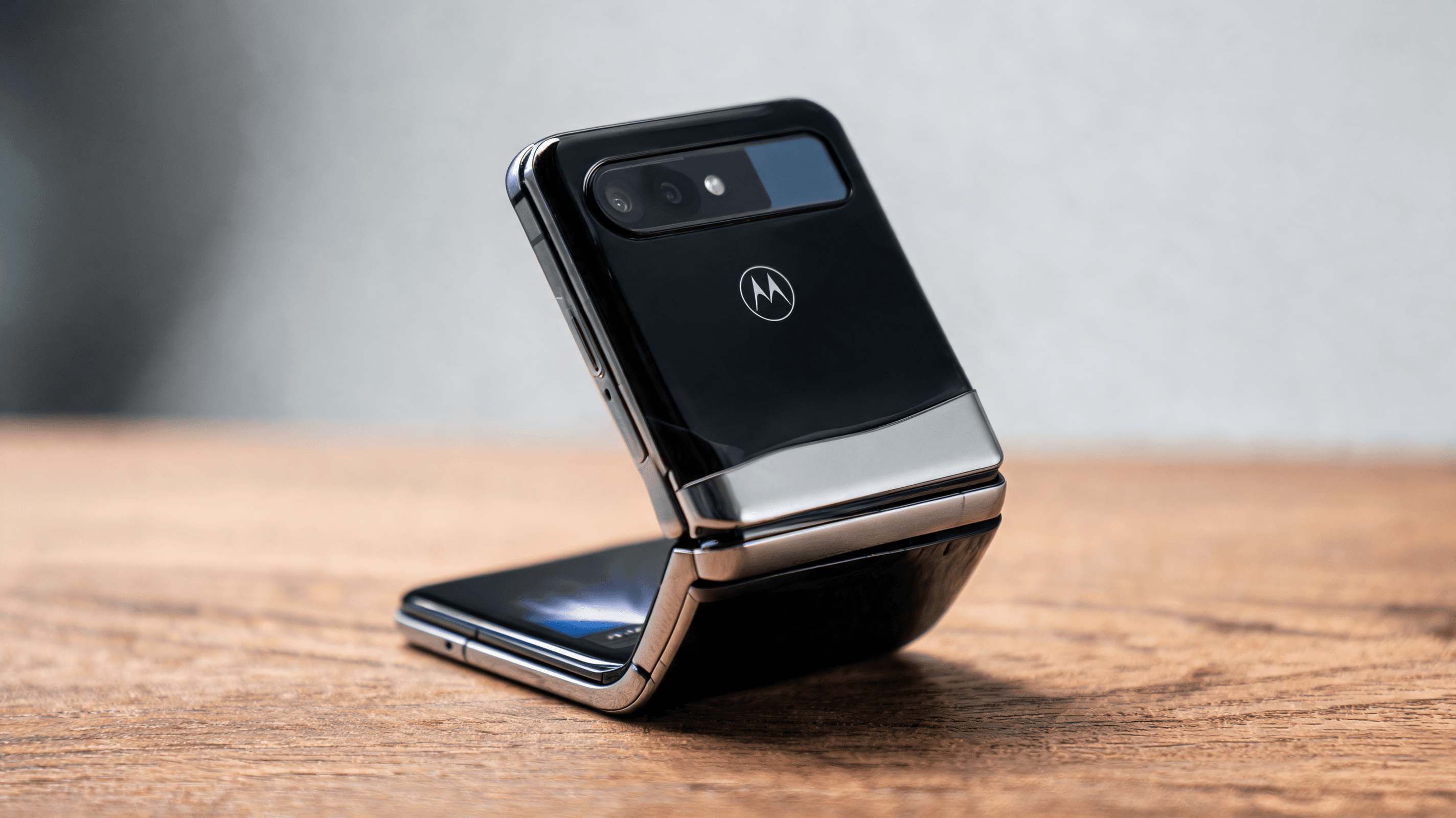 A stylish, professional studio photograph of the Motorola Razr foldable phone in a half-folded state
