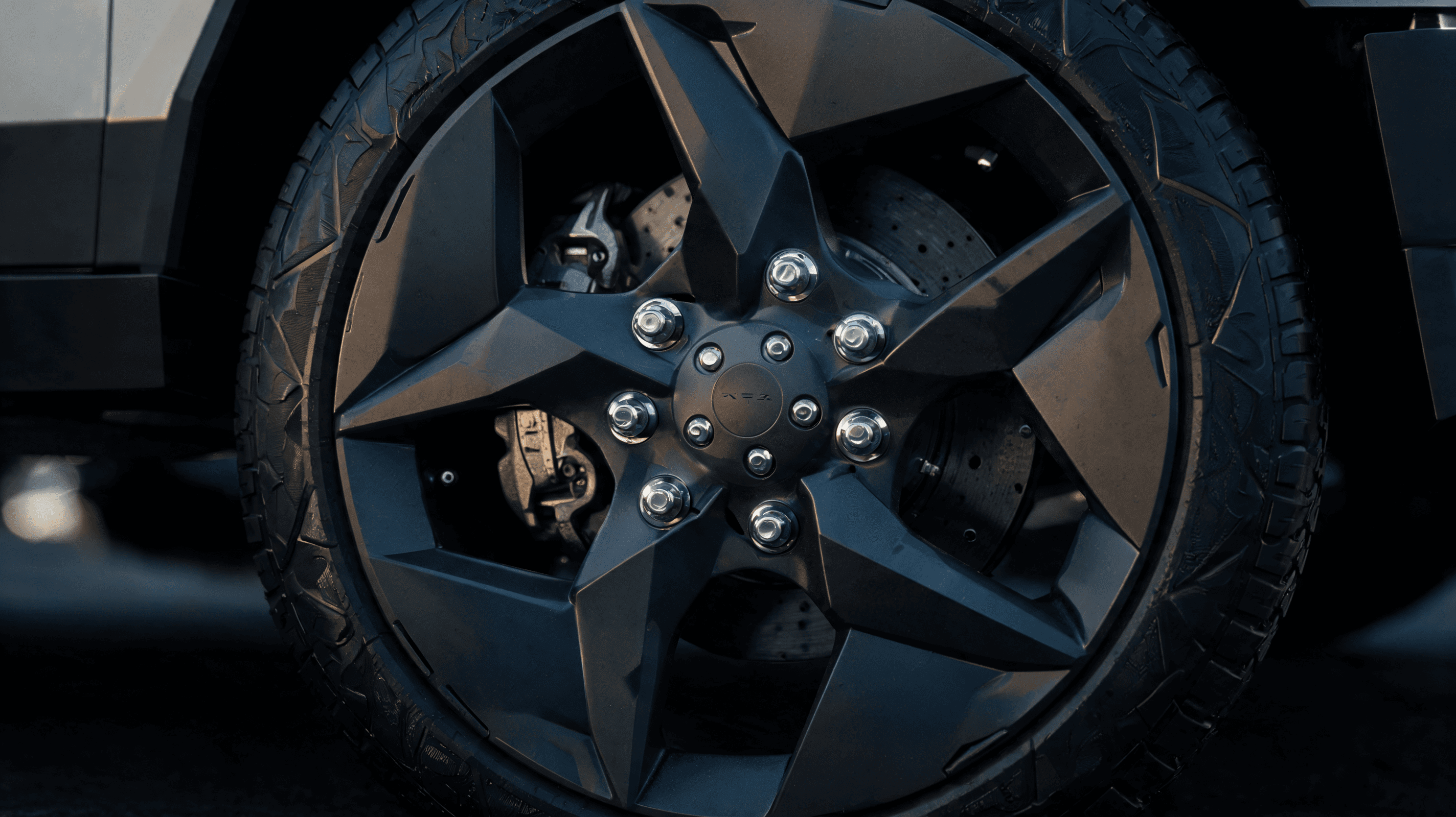 A close-up shot of a Tesla Cybertruck's wheel, highlighting the mechanical assembly and lug nuts, ci